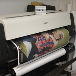 Powielarnia MADAS - Drukarka wielkoformatowa Canon drukuje zdjęcie obejmującej się pary, obok rolki papieru, na drukarce napis MADAS.