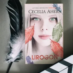 Okładka książki Cecelii Ahern 'Lirogon' z piórami i klapsem filmowym na szarym tle.