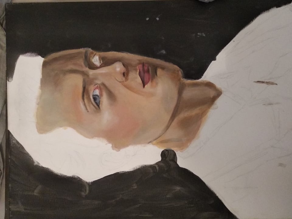 Portret kobiety w trakcie malowania akrylem na płótnie, widoczne szkice i niedokończone partie, ciemne tło kontrastuje z jasną karnacją modelki.