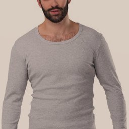 ZPHU SZATA II Adam Tadeusz Szawłowski - Mężczyzna prezentuje szarą koszulkę z długim rękawem i szerokim dekoltem, uszytą z prążkowanej dzianiny, na beżowym tle.