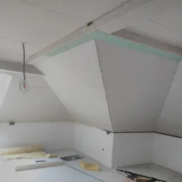 Poddasze w trakcie adaptacji: widoczne ocieplenie wełną mineralną, płyty karton-gips na skosach dachu, konstrukcja metalowa na podłodze, okno dachowe.