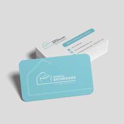 Business Partners Club - Stos wizytówek firmy remontującej łazienki, z logo przedstawiającym wannę wewnątrz obrysu domu, na jasnoszarym tle.