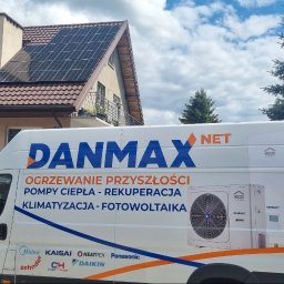 DANMAX Spółka z o.o. - Dom z panelami słonecznymi na dachu, częściowo zasłonięty przez białą furgonetkę z reklamą firmy instalacyjnej Danmax NET, oferującej ogrzewanie, pompy ciepła i klimatyzację.