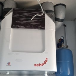 DANMAX Spółka z o.o. - Centrala rekuperacyjna Zehnder ComfoAir Q z podłączonymi przewodami wentylacyjnymi i instalacją hydrauliczną, widoczne manometry i zbiorniki wyrównawcze.