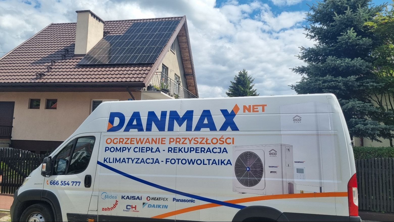 Dom z panelami słonecznymi na dachu, częściowo zasłonięty przez białą furgonetkę z reklamą firmy instalacyjnej Danmax NET, oferującej ogrzewanie, pompy ciepła i klimatyzację.