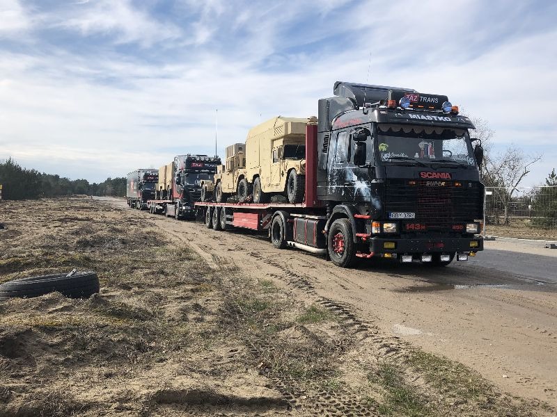 Ciężarówki Scania przewożące wojskowe pojazdy opancerzone na niskopodwoziowych naczepach, widoczne oznaczenia firmy przewozowej 'AZ Trans Miastko'.