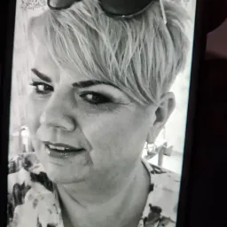 Czarno-białe zdjęcie portretowe kobiety z okularami na głowie, zrobione telefonem komórkowym.