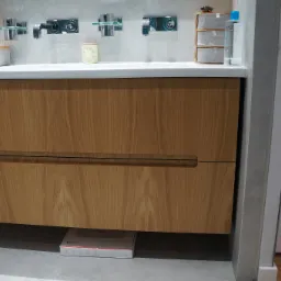 Nowoczesna łazienka z drewnianą szafką pod umywalką z dwoma szufladami i wagą łazienkową pod spodem.