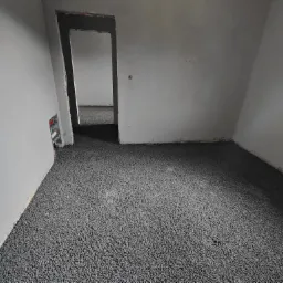 Świeżo wylana, szara, samopoziomująca masa na podłodze w surowym pomieszczeniu z widocznymi instalacjami elektrycznymi przy ścianie.