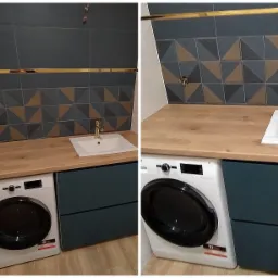 Łazienka z drewnianym blatem, umywalką nablatową i pralką pod blatem, ciemne szafki z dwoma szufladami, mozaika na ścianie z geometrycznym wzorem w odcieniach szarości i brązu, złota armatura.