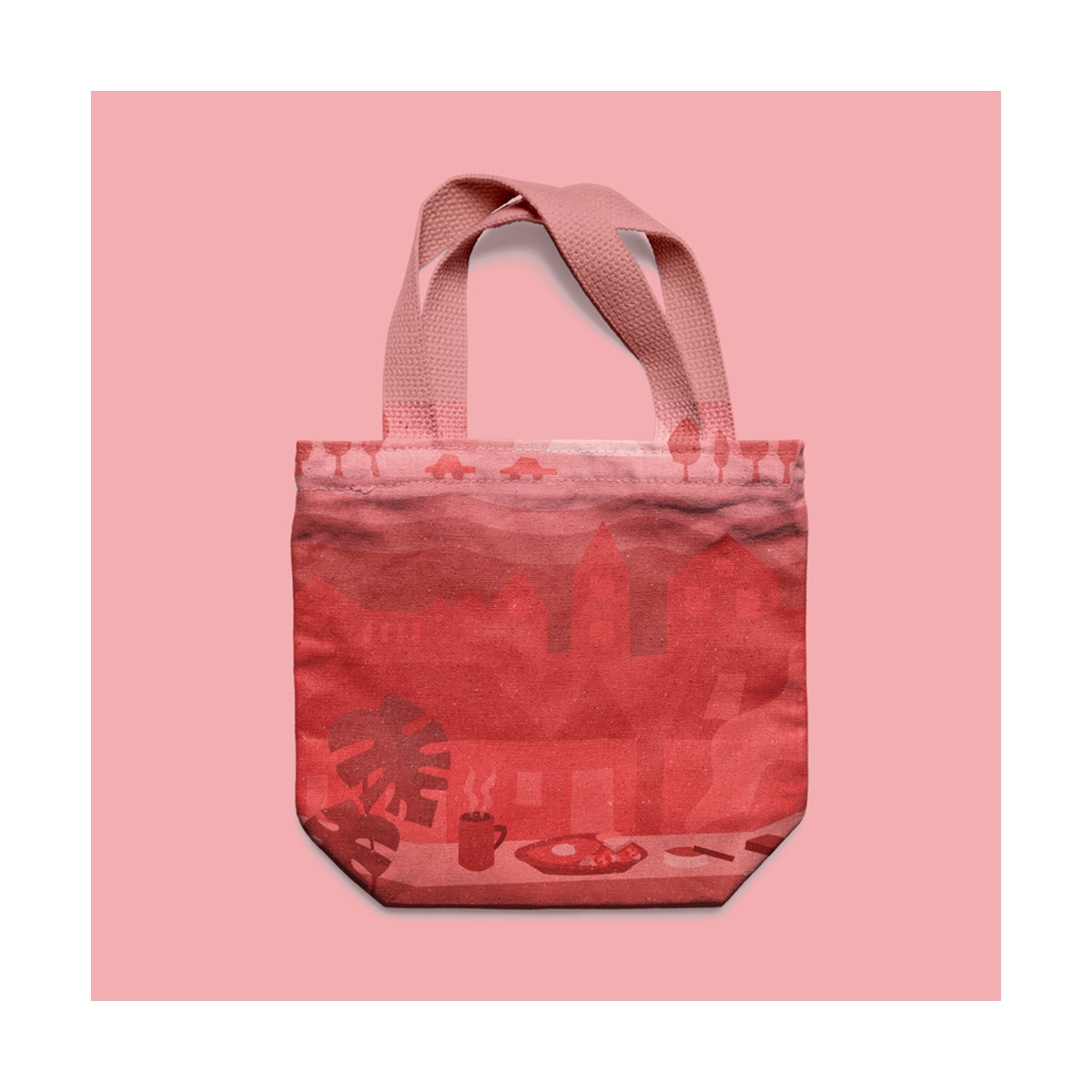 Różowa torba bawełniana z nadrukiem w odcieniach czerwieni przedstawiającym panoramę miasta, filiżankę kawy i liść monstery.