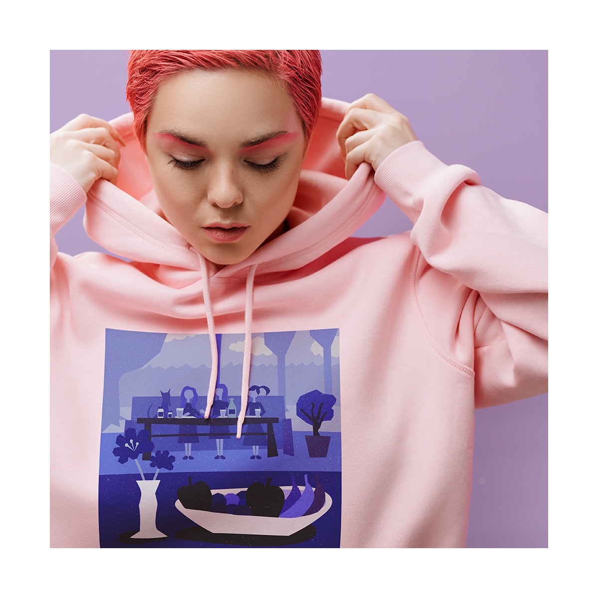 Osoba z różowymi włosami w różowej bluzie z kapturem, na której nadrukowano graficzny obrazek przedstawiający osoby siedzące przy stole, wazon z kwiatami i misę z owocami na fioletowym tle.