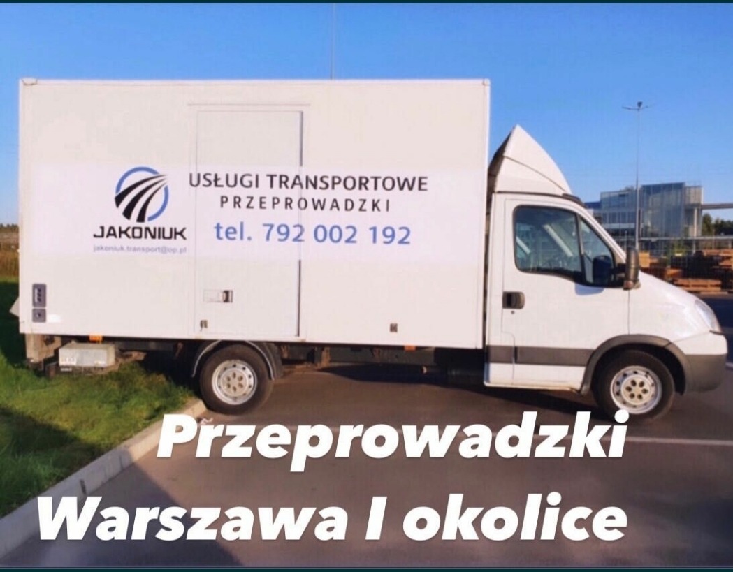 Biała furgonetka z reklamą usług transportowych i przeprowadzkowych firmy Jakoniuk, zaparkowana na parkingu z budynkiem biurowym w tle.