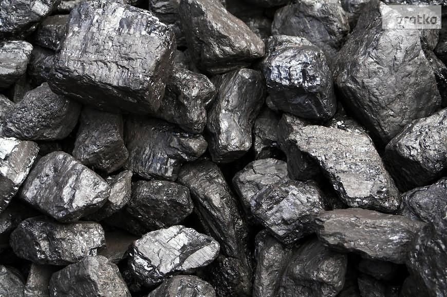 Kupa błyszczącego, czarnego węgla kamiennego o nieregularnych kształtach, oświetlona z góry, ukazująca teksturę powierzchni.