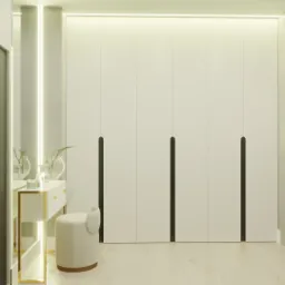 Minimalistyczna garderoba z białymi frontami i długimi, czarnymi uchwytami, uzupełniona toaletką z lustrem i okrągłym pufem w jasnych barwach, oświetlona listwą LED.