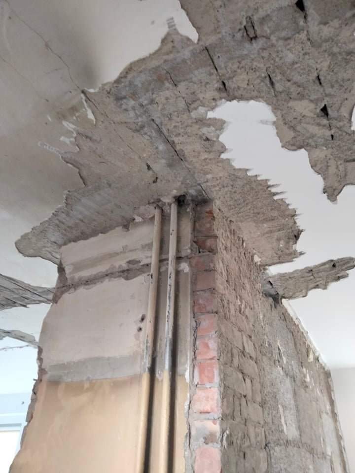 Częściowo zdemontowana ściana z cegły i fragment zniszczonego sufitu w trakcie prac w Szczecinie, widoczne rury i odsłonięta konstrukcja.