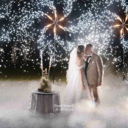 JK-Fotografia Krzysztof Jastrzębski - Pocałunek pary młodej na tle nocnego nieba rozświetlonego sztucznymi ogniami i tortu weselnego na stole. Romantyczna atmosfera.