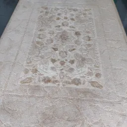 Beżowy dywan z kwiatowym wzorem, widoczne ślady po praniu i odkurzacz na podłodze