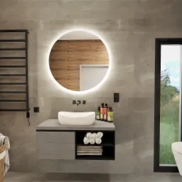 Nowoczesna łazienka z okrągłym lustrem podświetlanym LED, szarą armaturą i elementami drewna, widok na zewnątrz przez okno z czarną ramą.