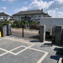 Ddshops Jarosław Dębski - Czarna, metalowa brama wjazdowa z dekoracyjnymi elementami, zamontowana na posesji w Tarnowskich Górach, z widocznym fragmentem białego samochodu dostawczego w tle.