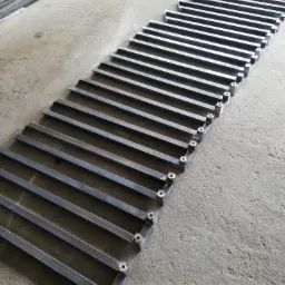 Przygotowane elementy metalowe, prawdopodobnie do balustrady lub ogrodzenia, leżące na betonowej posadzce warsztatu, widoczne otwory montażowe.