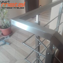SMART METAL Tomasz Krause - Fragment balustrady ze stali nierdzewnej z geometrycznym wypełnieniem, widok z góry, na podłodze poziomica i butelka z napojem, w tle roślina doniczkowa.