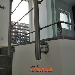 SMART METAL Tomasz Krause - Nierdzewna balustrada schodowa z poprzecznymi prętami, mocowana do ściany za pomocą okrągłych uchwytów, widoczne schody z szarego kamienia i logo firmy Smart Metal Tomasz Krause.