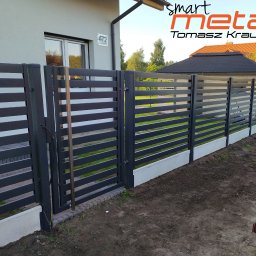 SMART METAL Tomasz Krause - Nowoczesne, poziome ogrodzenie metalowe w kolorze grafitowym z bramą wjazdową, osadzone na betonowej podmurówce, z widocznym numerem domu 47/2 i logo firmy Smart Metal Tomasz Krause.