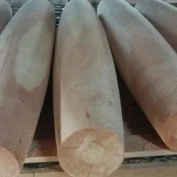 Blisko ujęte, obrobione drewniane bale o zaokrąglonych końcach, ułożone równolegle, ukazujące strukturę drewna i gotowe do dalszej obróbki lub wykorzystania.