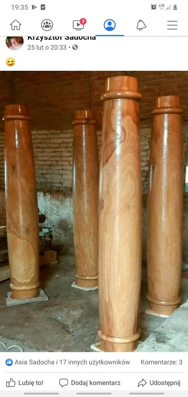 Polerowane drewniane kolumny o toczonych podstawach i zwieńczeniach, ustawione w pomieszczeniu z ceglaną ścianą w tle, prawdopodobnie przygotowane do montażu w altanie lub pergoli.