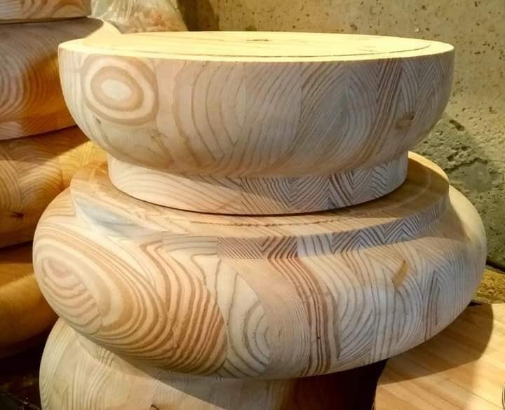 Toczone elementy drewniane z widocznym usłojeniem, prawdopodobnie nogi do mebli, ułożone jeden na drugim.
