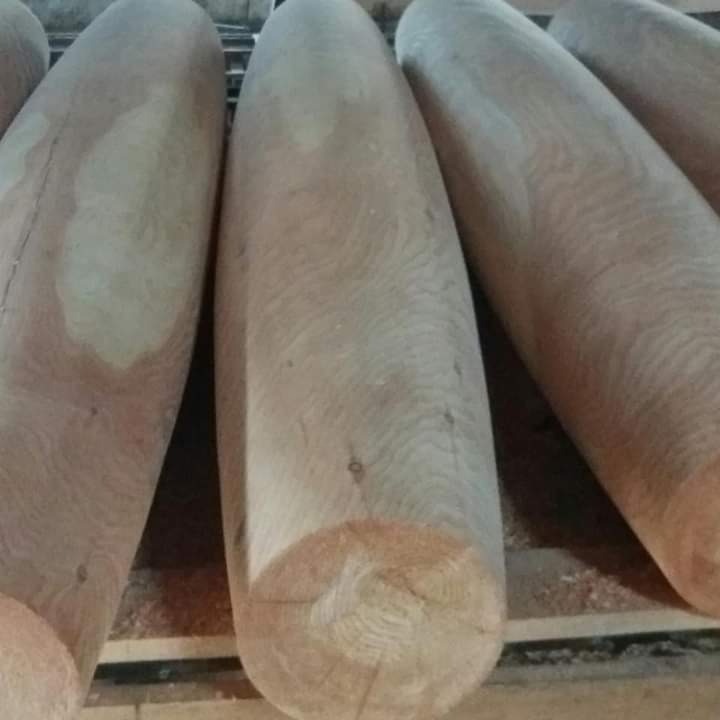 Blisko ujęte, obrobione drewniane bale o zaokrąglonych końcach, ułożone równolegle, ukazujące strukturę drewna i gotowe do dalszej obróbki lub wykorzystania.