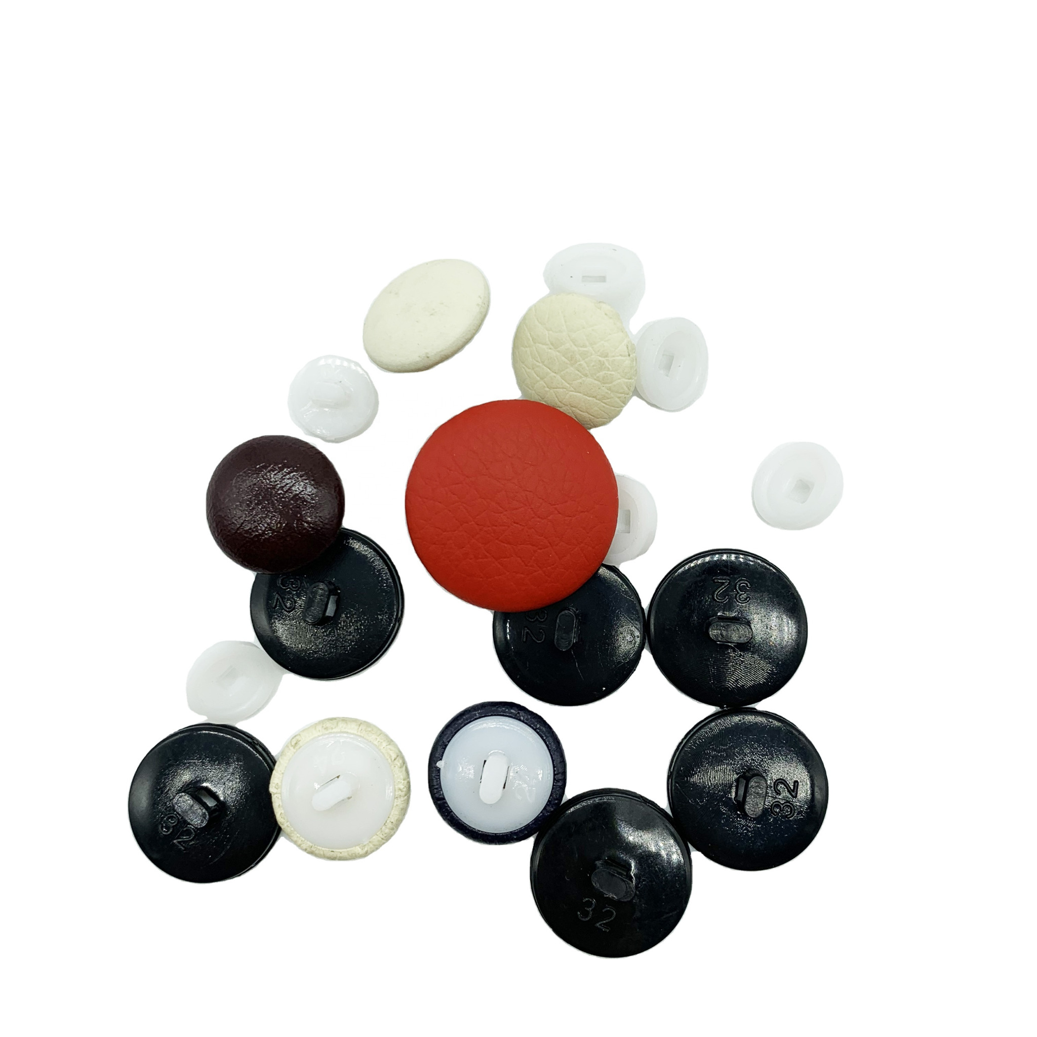 Zestaw różnorodnych guzików: czarne z numerem 32, czerwony skóropodobny, brązowy lakierowany, białe matowe i przezroczyste, ułożone na białym tle.