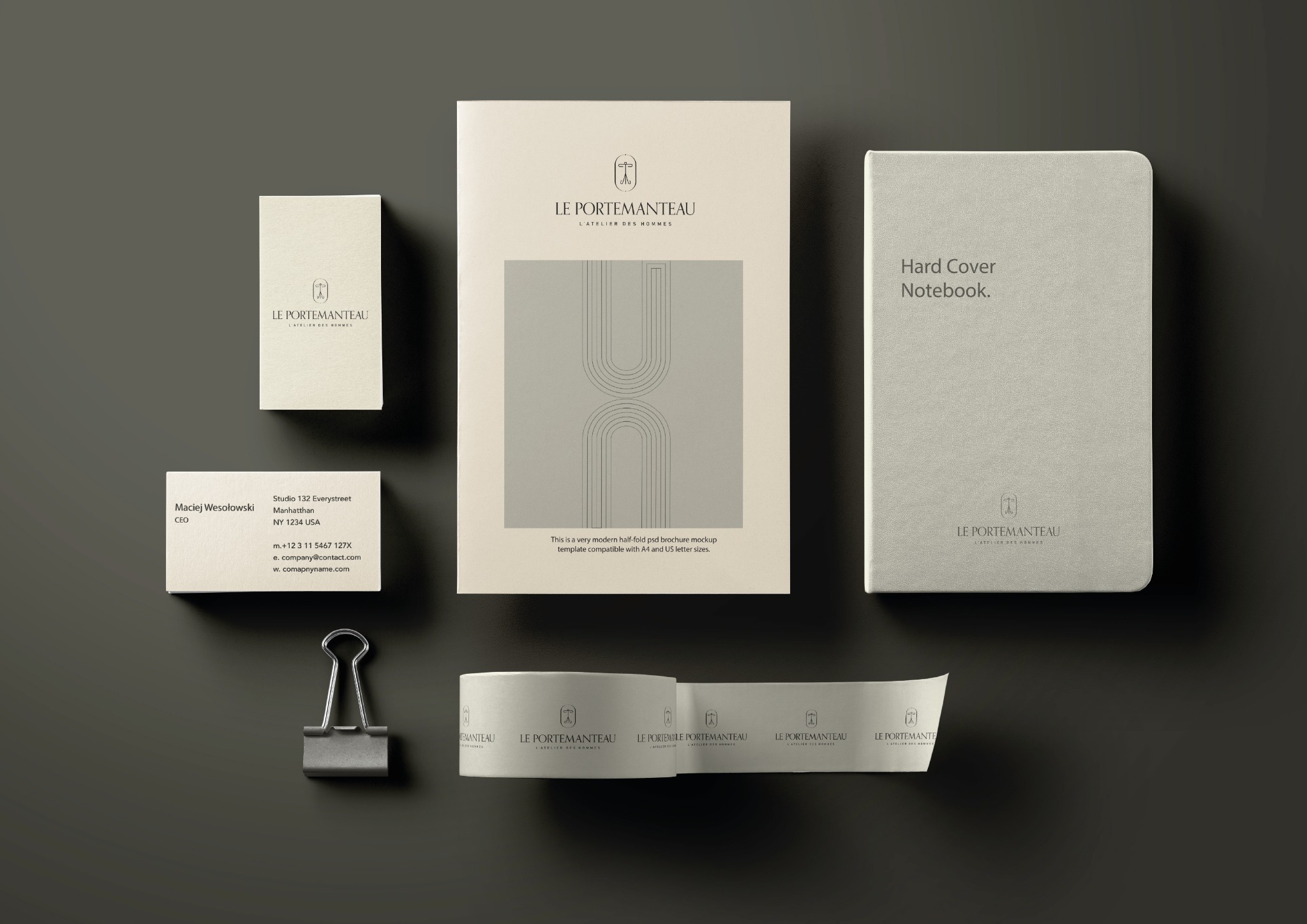 Mockup identyfikacji wizualnej firmy 'Le Portemanteau' z wizytówką, notatnikiem w twardej oprawie, broszurą i taśmą z logo, na ciemnoszarym tle.