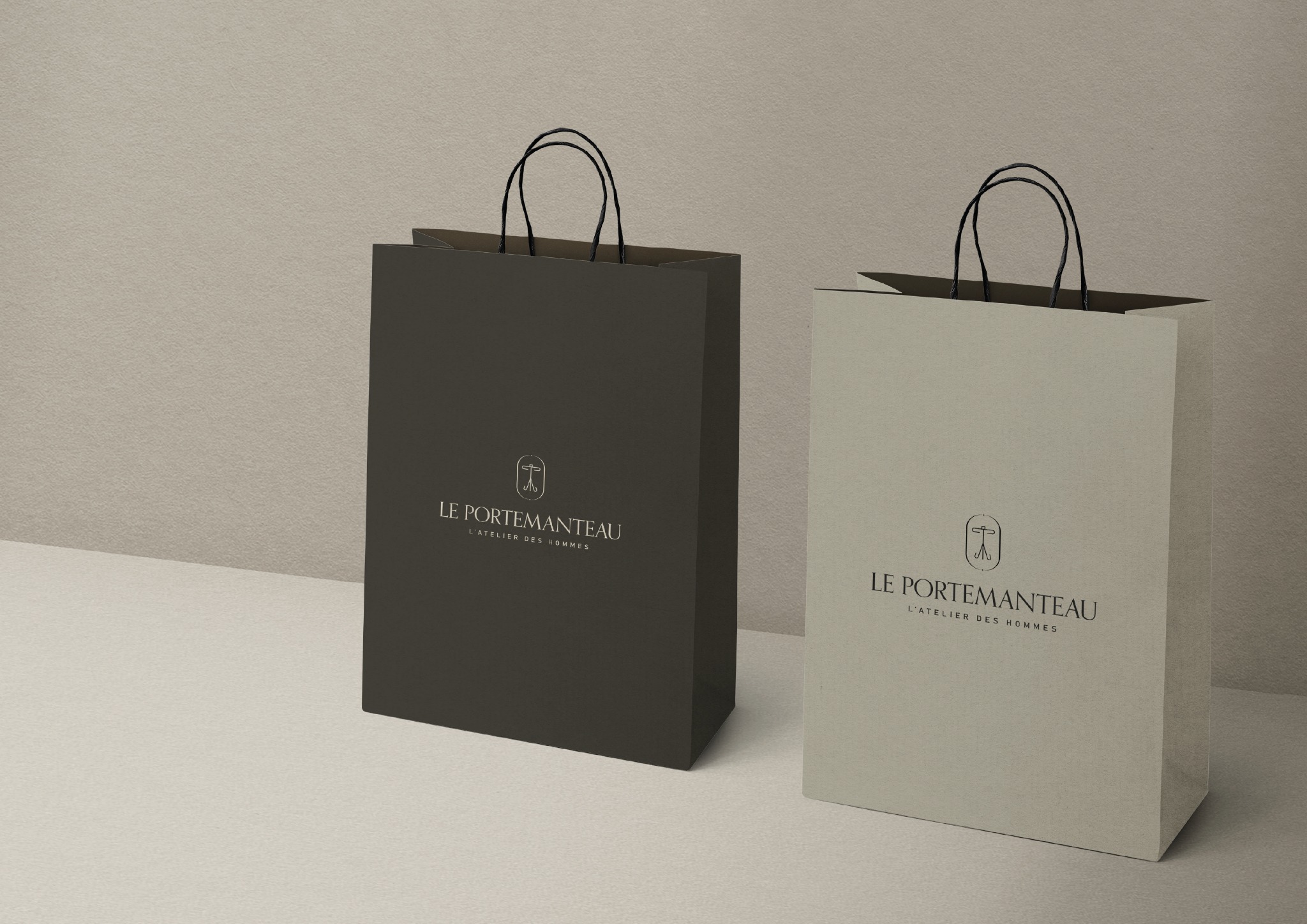 Dwie papierowe torby na zakupy z logo 'Le Portemanteau' w odcieniach szarości, ustawione obok siebie na jasnym tle. Elegancki design, minimalizm i subtelne logo.