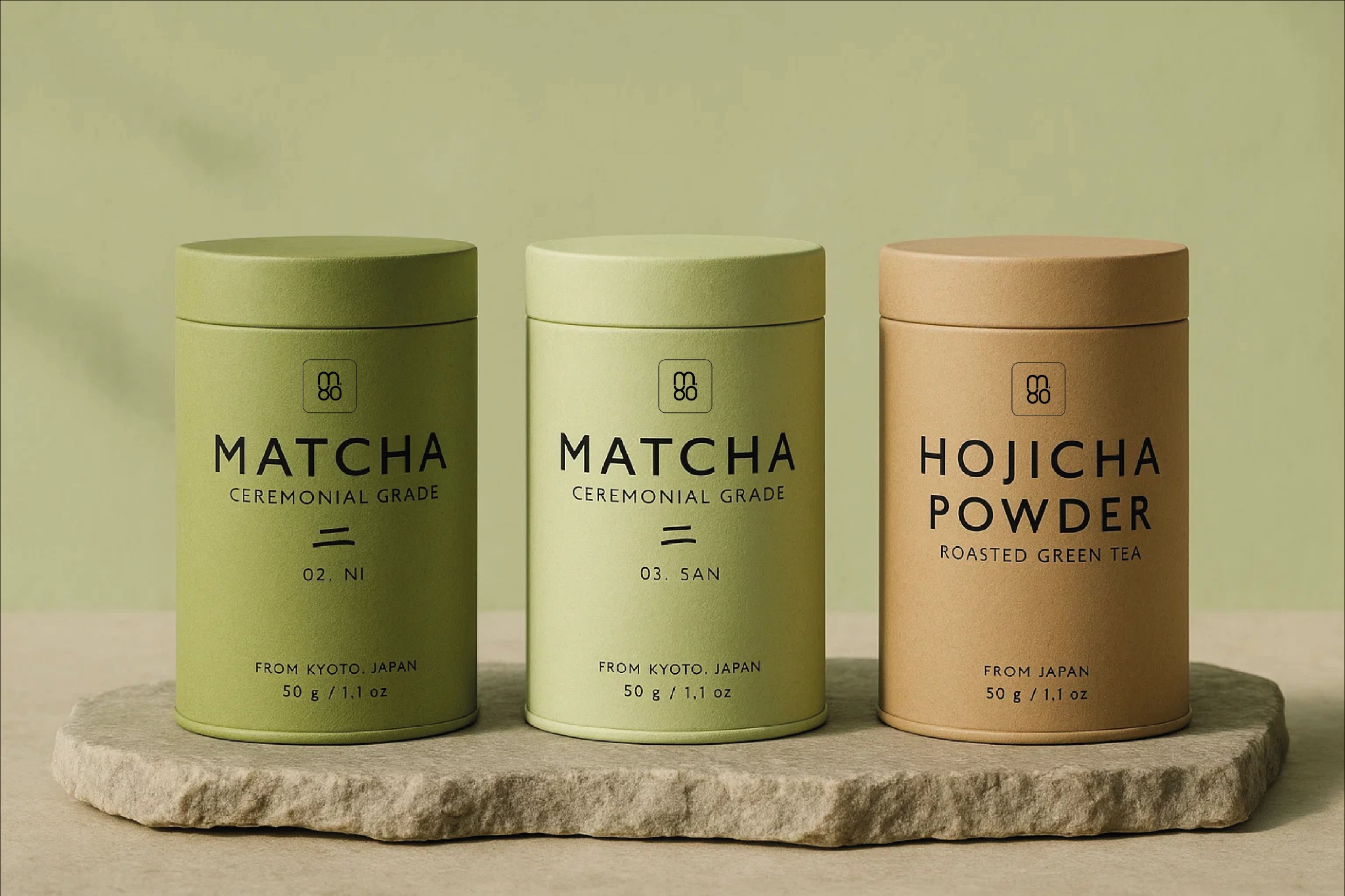Trzy minimalistyczne puszki z herbatą Matcha i Hojicha Powder na kamiennej podstawie, z logo i napisem 'From Kyoto, Japan'. Stonowana kolorystyka, proste wzornictwo.