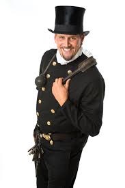 Uśmiechnięty mężczyzna w tradycyjnym stroju kominiarskim z cylindrem, trzymający szczotkę kominiarską na ramieniu, na białym tle.