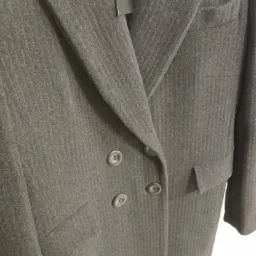 Długi, szary płaszcz dwurzędowy z wełny w delikatny prążek, widoczne klapy, kieszenie i trzy guziki, z metką.