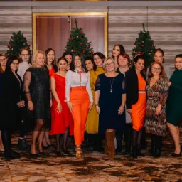 Grupowe zdjęcie zespołu w różnorodnych strojach na tle dekoracji świątecznych, być może z firmowego spotkania.