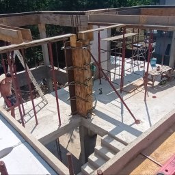 BDP Polska Daniel Budek - Wysoki kąt widzenia na plac budowy z widocznymi szalunkami drewnianymi, rusztowaniami i pracownikiem w tle, ukazujący etap wznoszenia konstrukcji budynku.