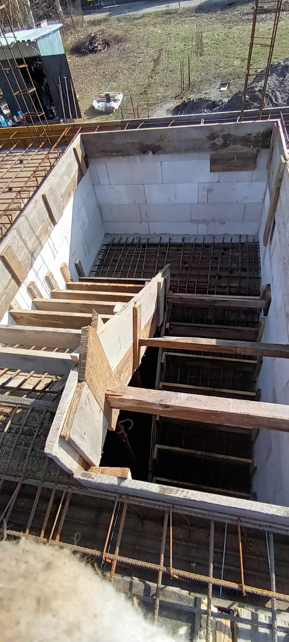 Wykop pod schody w trakcie budowy, z widocznym zbrojeniem, drewnianym szalunkiem i ścianami z bloczków betonowych.