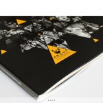 Czarno-biała abstrakcyjna grafika z żółtymi trójkątami na okładce książki/albumu, widoczny fragment tekstu w dolnym lewym rogu okładki.