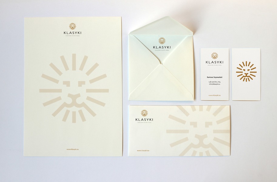 Komplet identyfikacji wizualnej firmy Klasyki: papier firmowy, koperta i wizytówki z minimalistycznym logo lwa w odcieniach beżu na białym tle.