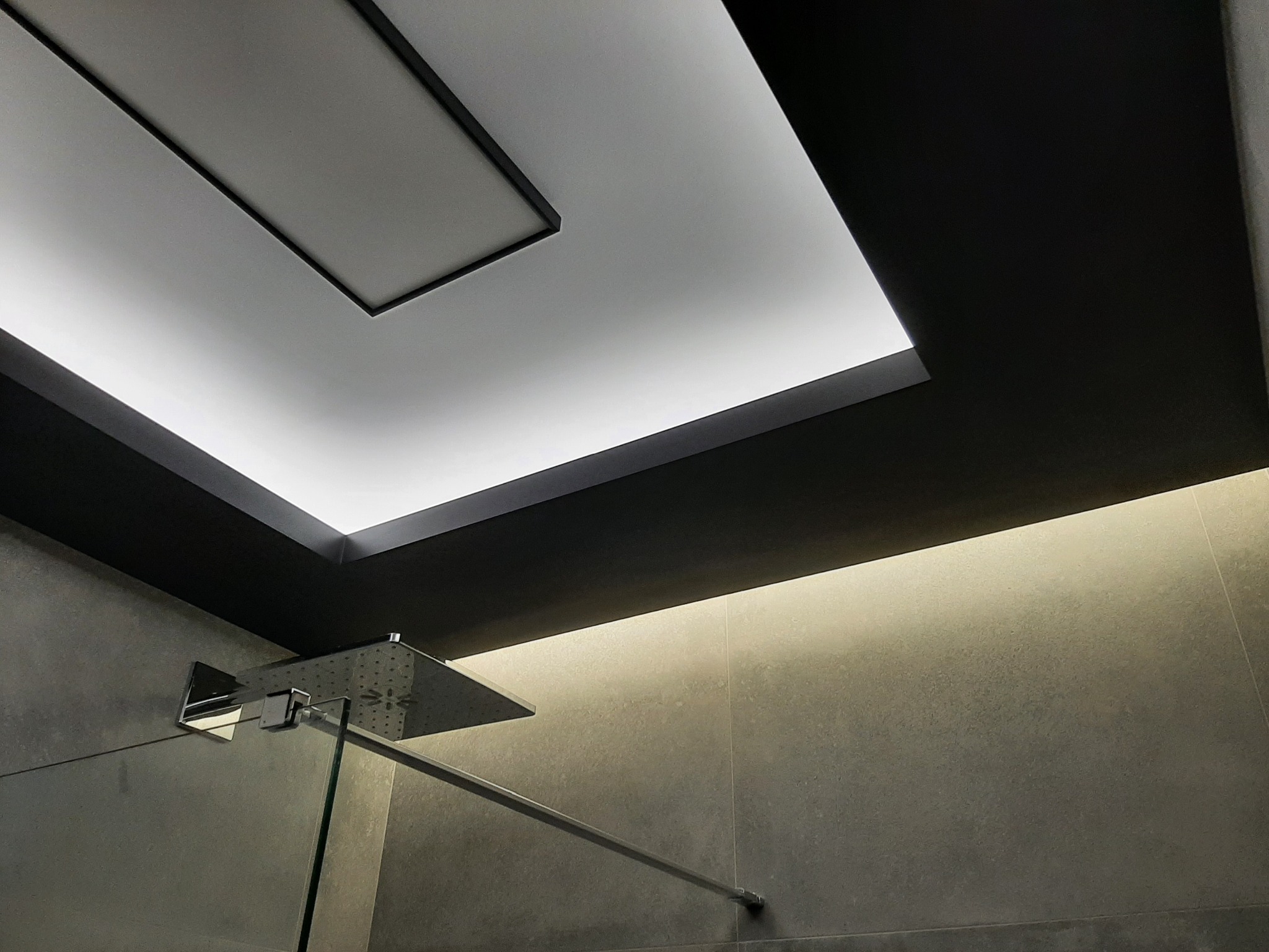 Nowoczesna kabina prysznicowa z deszczownicą i podświetlanym sufitem w odcieniach szarości.