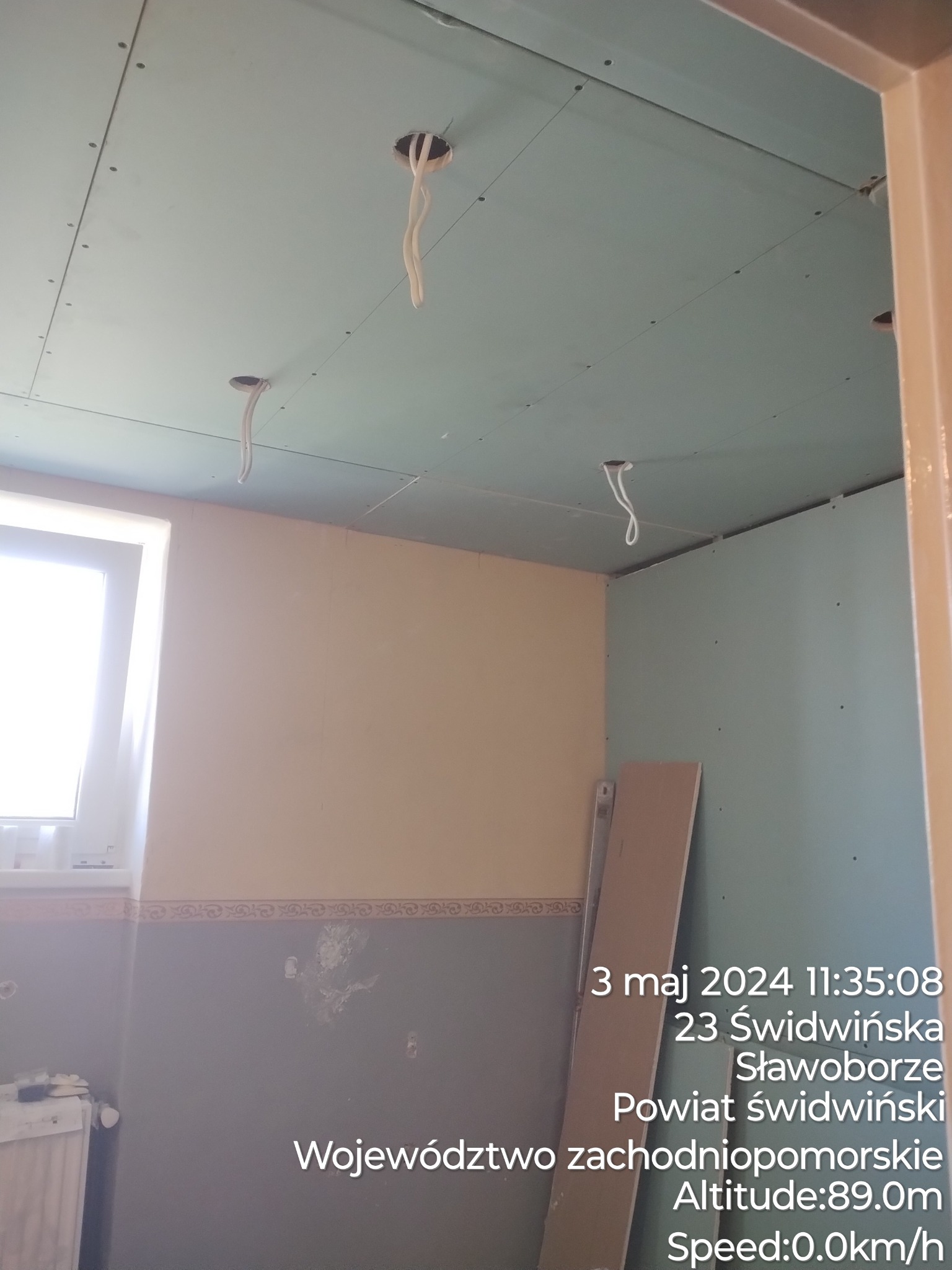 Wnętrze w trakcie prac wykończeniowych: sufit z płyt gipsowo-kartonowych z widocznymi otworami na oświetlenie, fragment ściany z widocznymi śladami po wcześniejszych dekoracjach, oraz fragmenty...