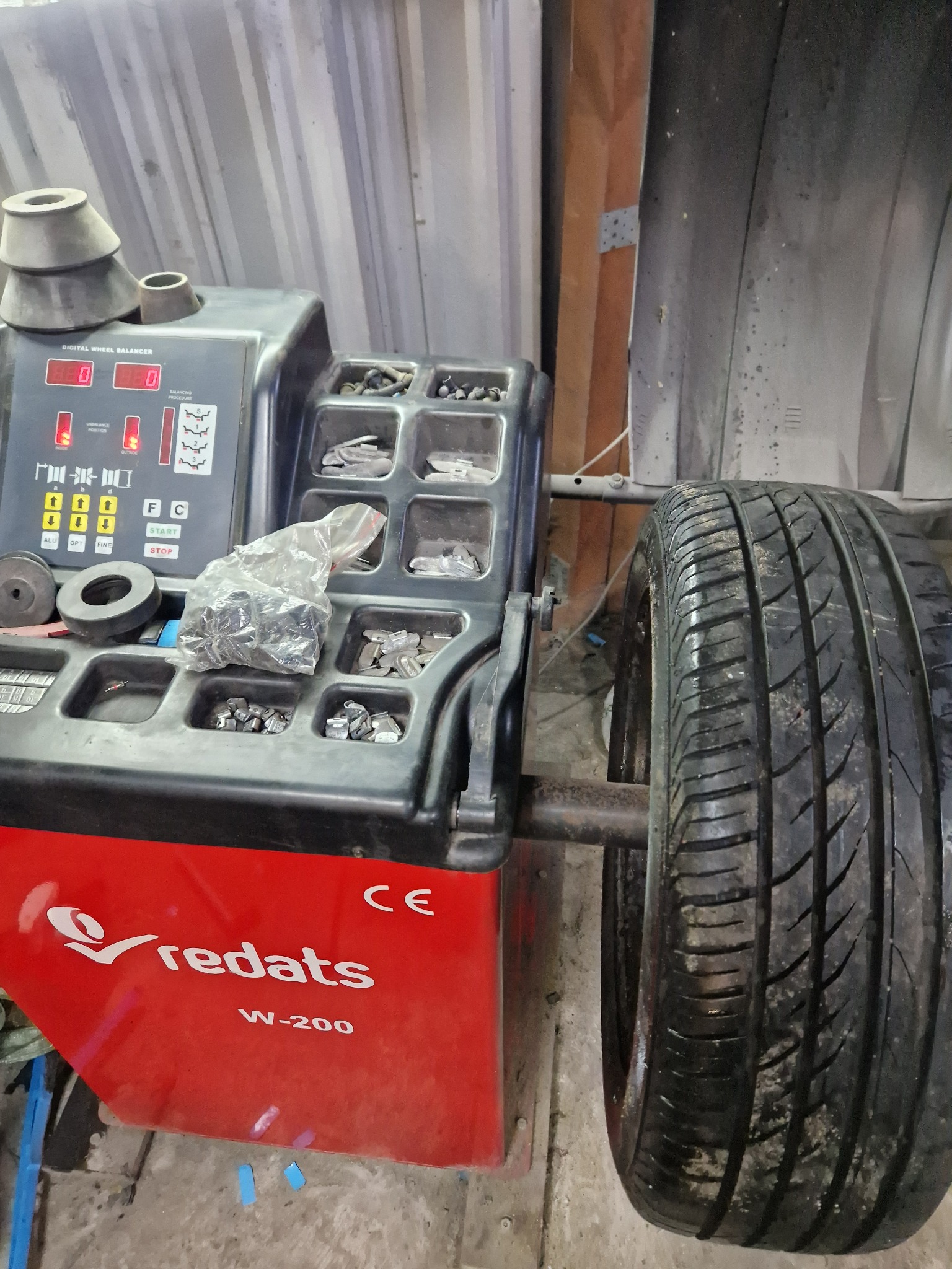 Wyważarka do kół Redats W-200 z założoną oponą, widoczne ciężarki do wyważania w przegródkach urządzenia.