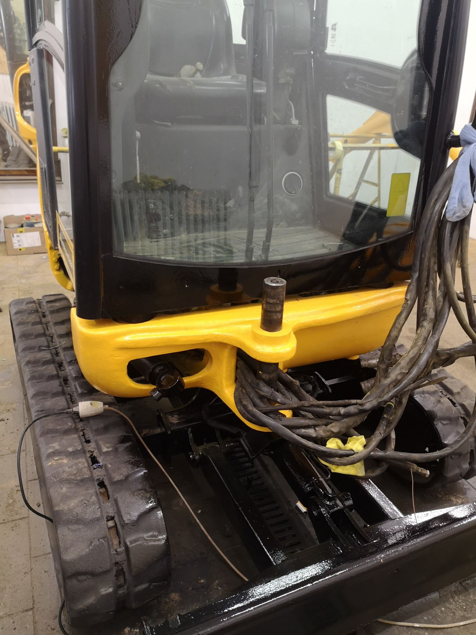 Odnowiona kabina małej koparki w kolorze żółto-czarnym, widoczne nowe przewody i świeżo pomalowane gąsienice.