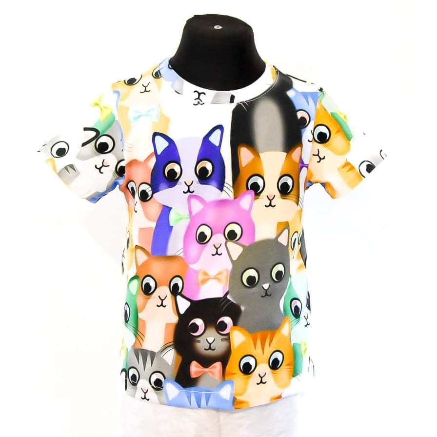 Biała koszulka dziecięca z kolorowym nadrukiem stylizowanych kotów na czarnym manekinie, widok z przodu.