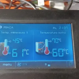 Ekran sterownika kotła grzewczego wyświetlający temperaturę mieszacza i kotła, z widocznymi wartościami 45°C i 70°C oraz 61°C i 60°C, w otoczeniu obudowy z tworzywa sztucznego.