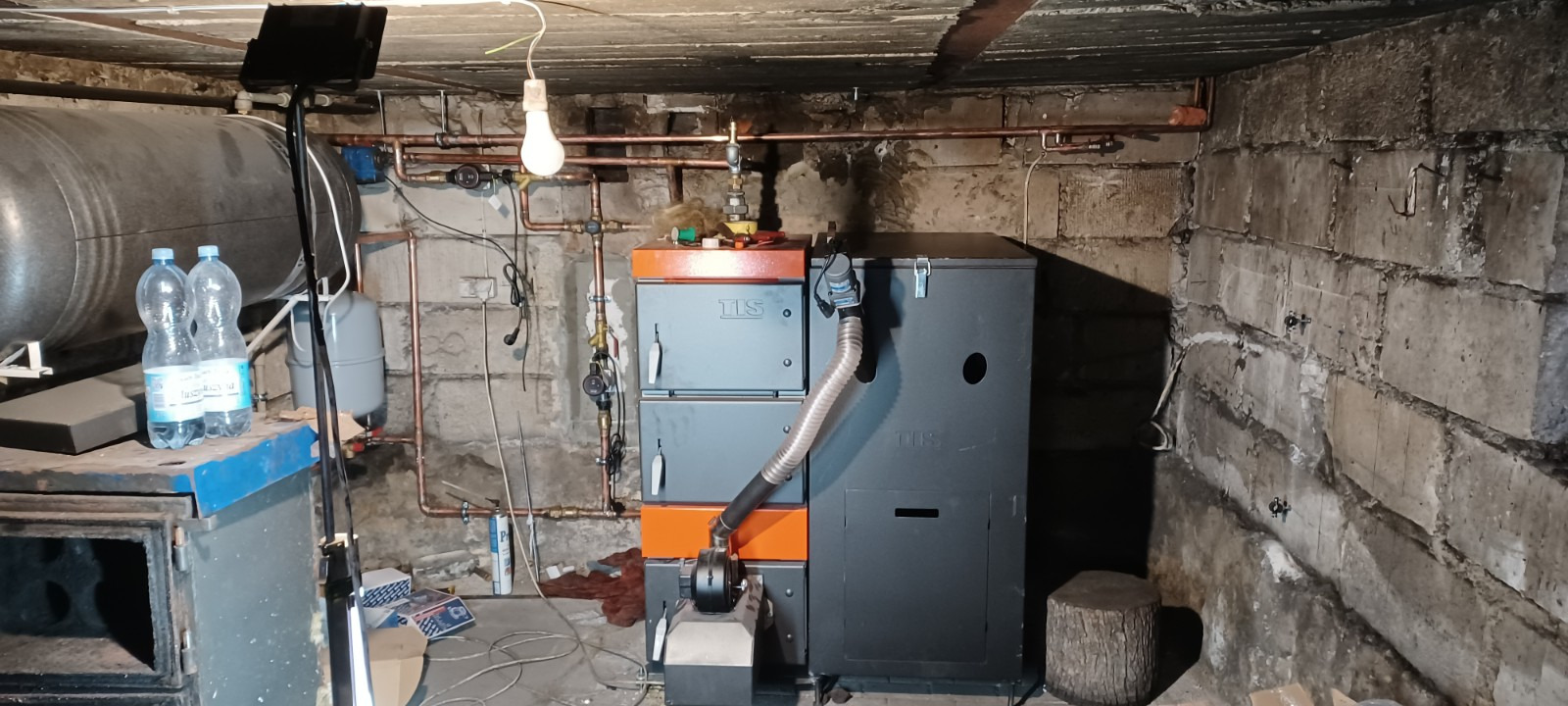 Kotłownia z kotłem na paliwo stałe TIS, instalacją grzewczą z miedzianych rur, oświetleniem roboczym i zapasem wody w plastikowych butelkach